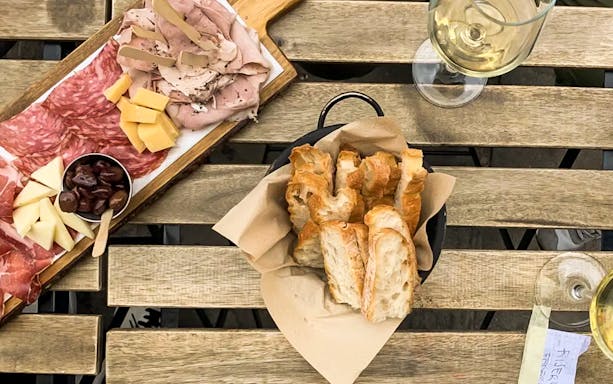 Charcuterie board with meats, cheeses, olives, and bread on a wooden table during a Venice food tour.
