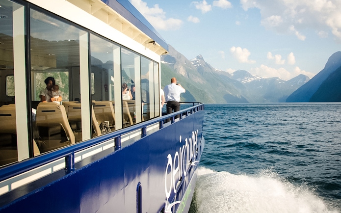 Guests on a boat enjoying the Silent Fjordcruise tour in Alesund, Norway with scenic mountain views.