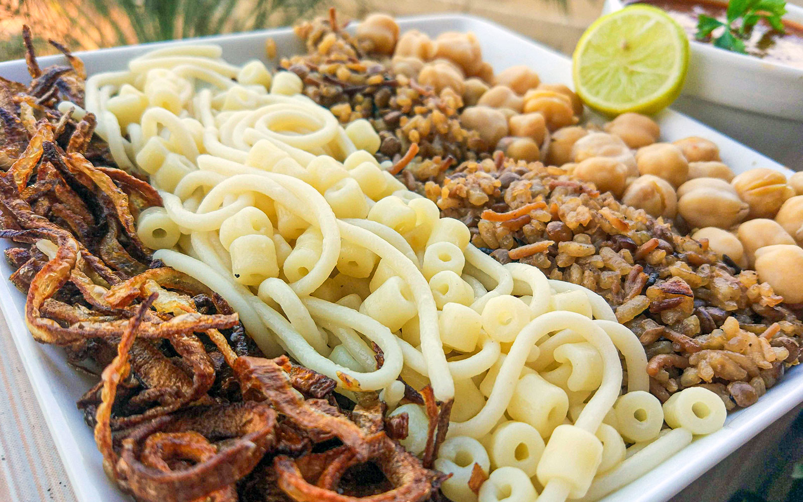 Koshari dish with pasta, rice, lentils, chickpeas, and fried onions, traditional Egyptian lunch.