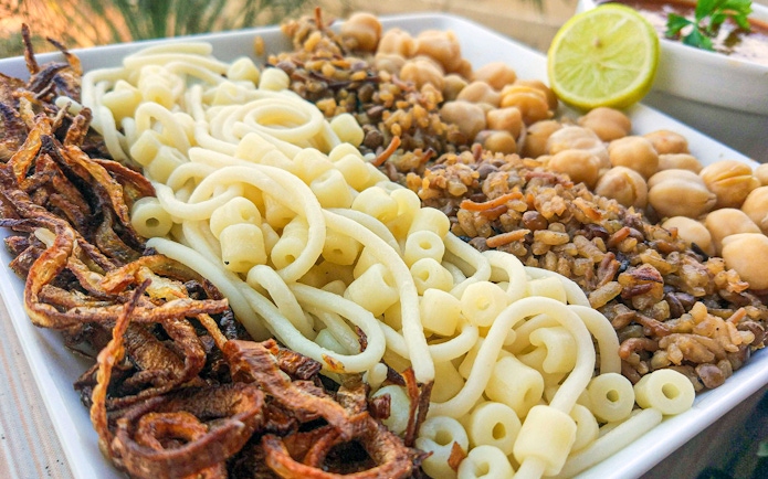 Koshari dish with pasta, rice, lentils, chickpeas, and fried onions, traditional Egyptian lunch.