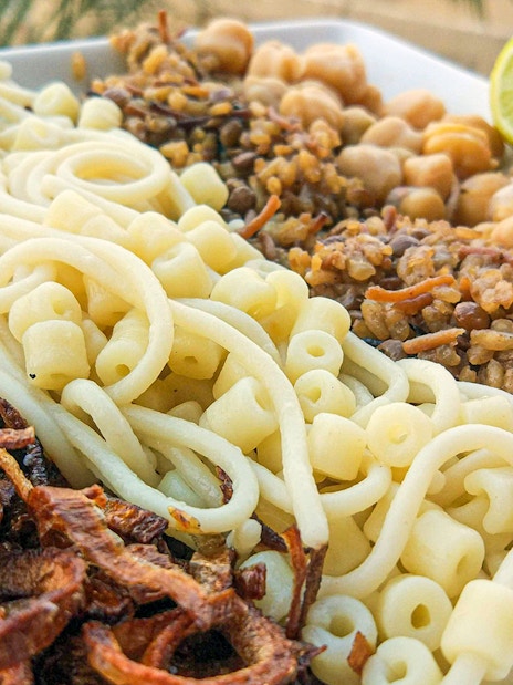 Koshari dish with pasta, rice, lentils, chickpeas, and fried onions, traditional Egyptian lunch.