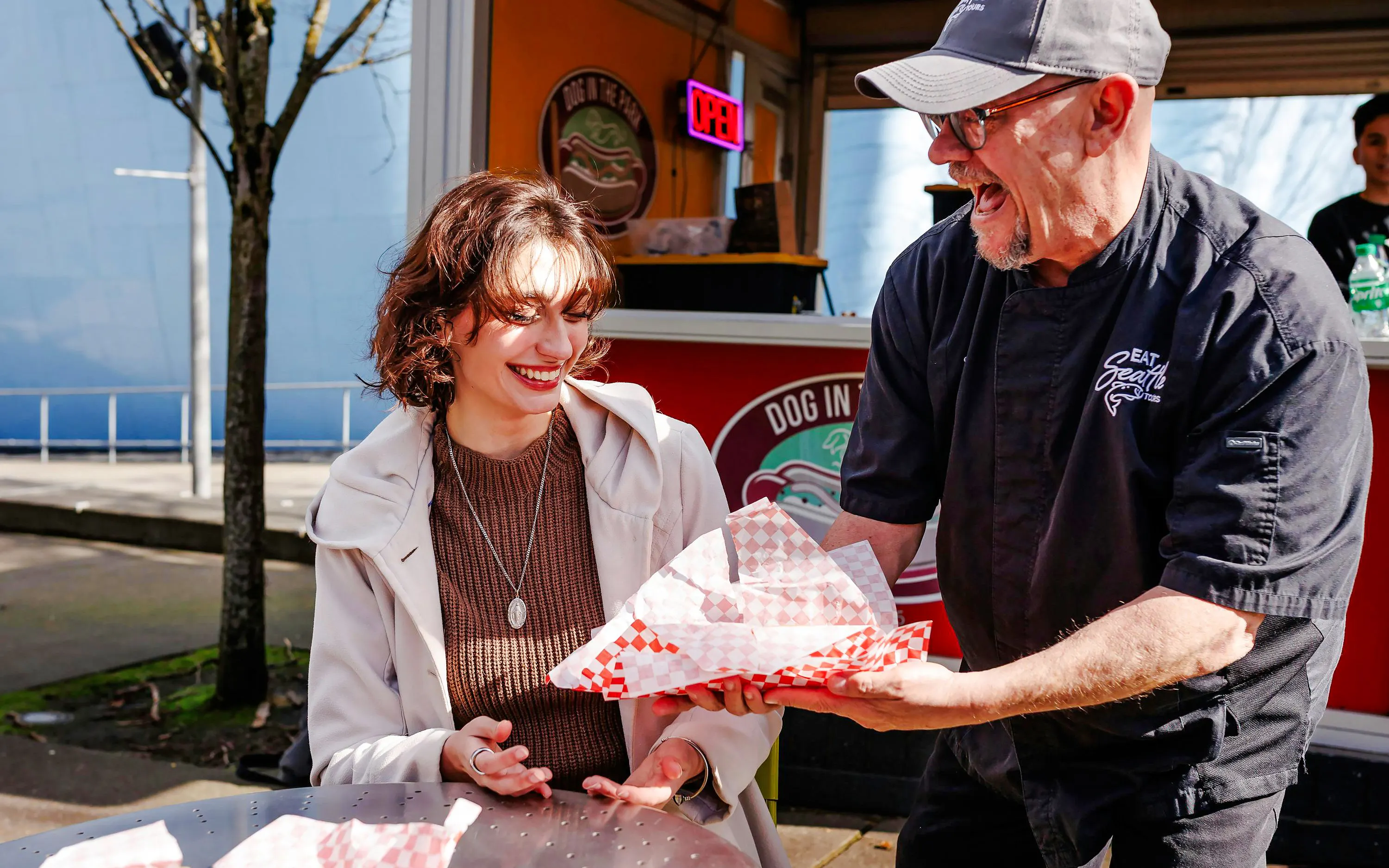 Seattle Center food vendor serving a smiling woman during the Space Needle food tour.
