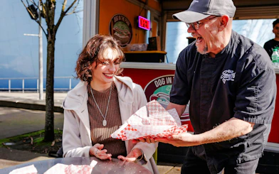 Seattle Center food vendor serving a smiling woman during the Space Needle food tour.
