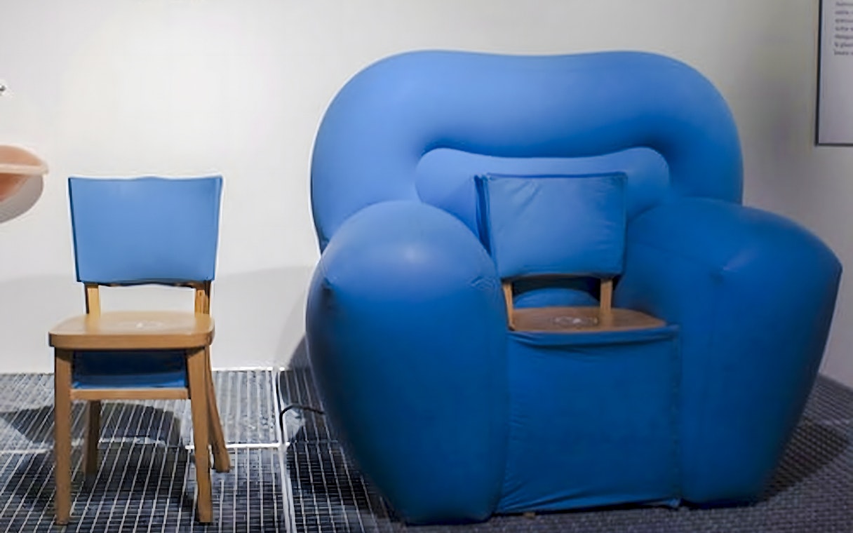 Blue inflatable armchair and wooden chair exhibit at Design Museum, Brussels.