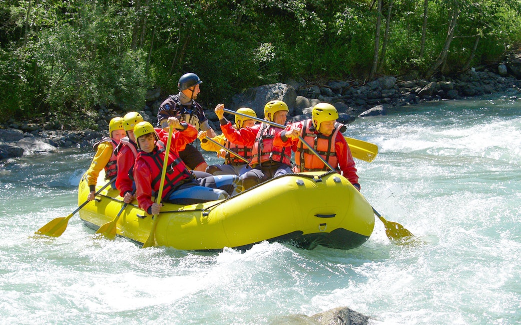 Group rafting through whitewater in a lush rainforest river.