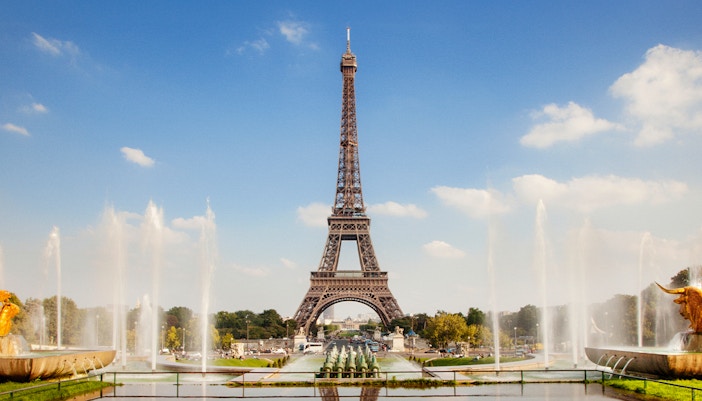 Eiffel Tower illuminated at dusk with cityscape in Paris, France.