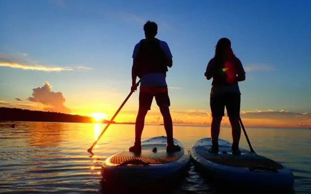 Two people paddleboarding at sunset on Iriomote Island, Okinawa.
