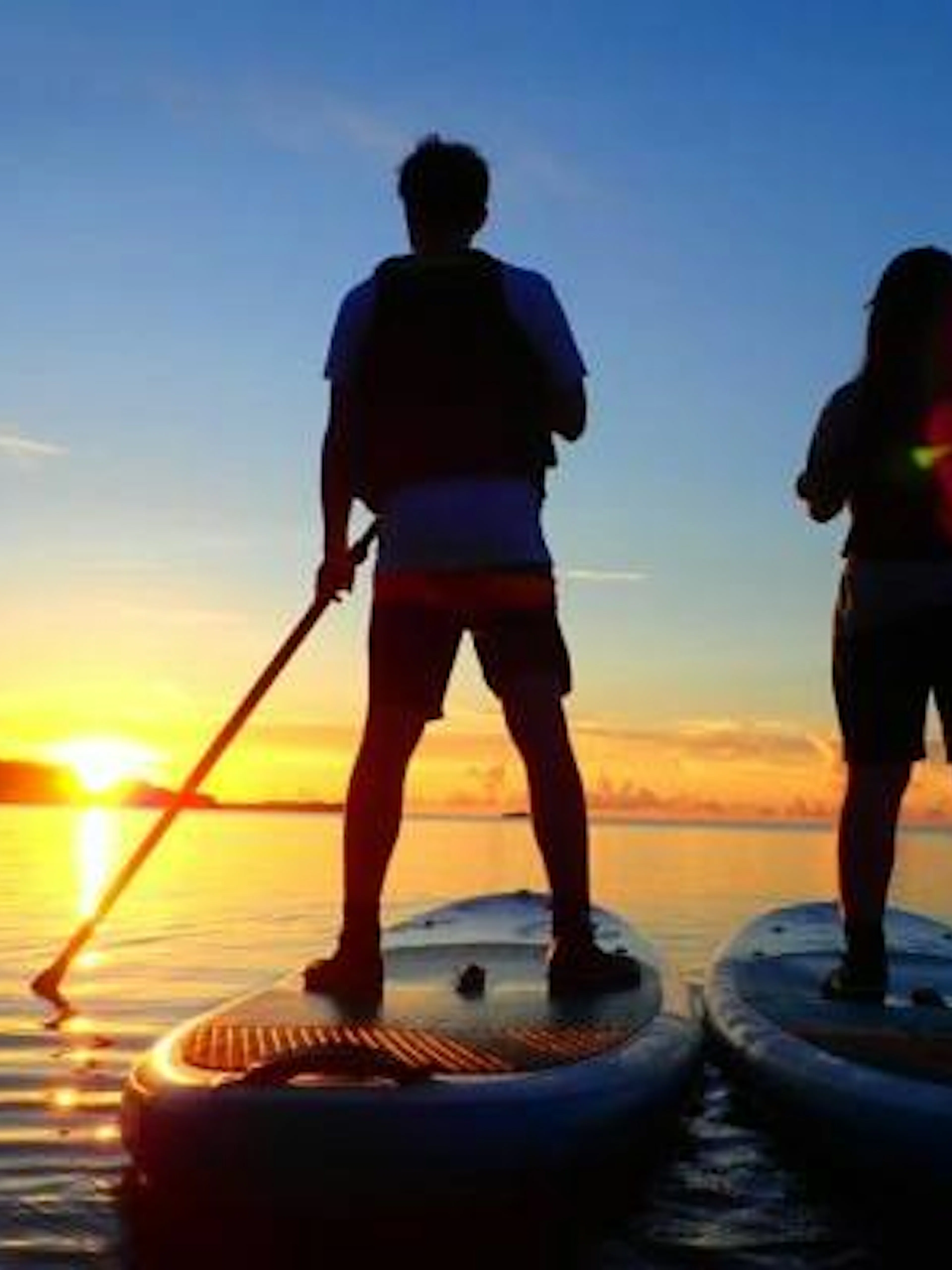 Two people paddleboarding at sunset on Iriomote Island, Okinawa.