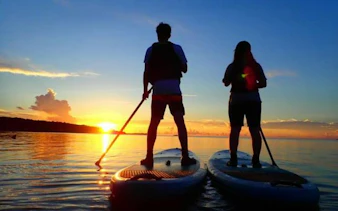 Two people paddleboarding at sunset on Iriomote Island, Okinawa.
