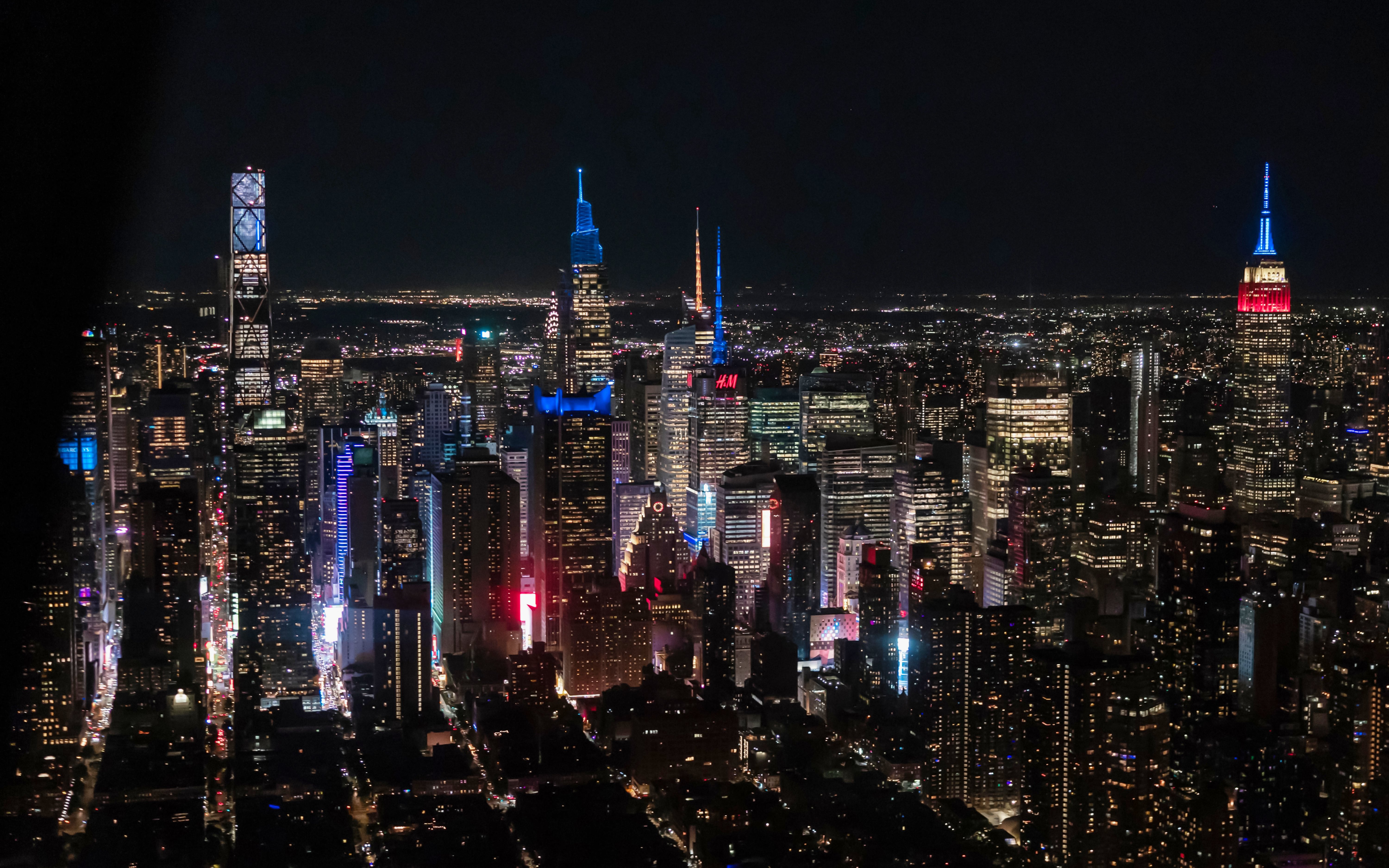 Aerial view of New York City skyline at night with illuminated skyscrapers.