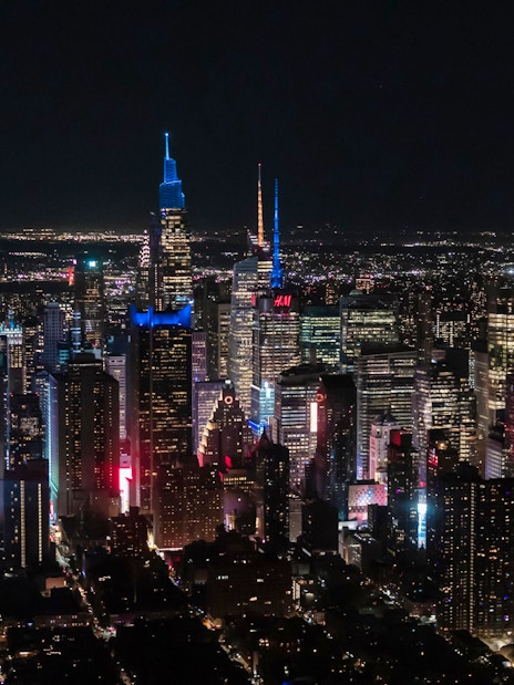 Aerial view of New York City skyline at night with illuminated skyscrapers.
