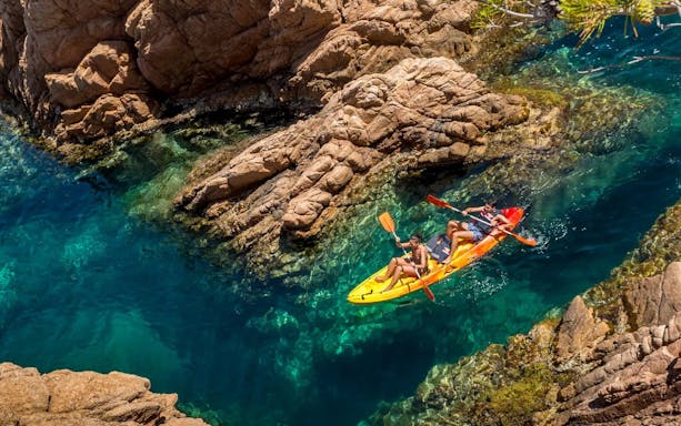 Visitors kayaking through rocky waters at Costa Brava.