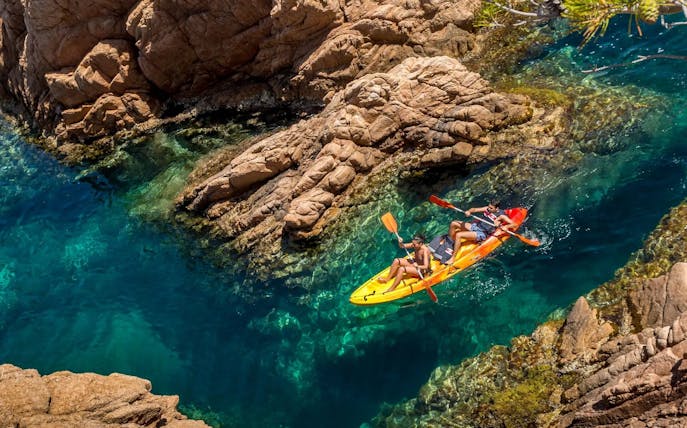 Visitors kayaking through rocky waters at Costa Brava.