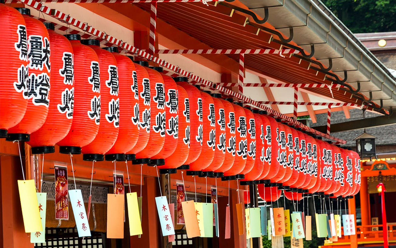 Red lanterns hanging in a row at a Kyoto shrine during a guided tour of the city's lanes.