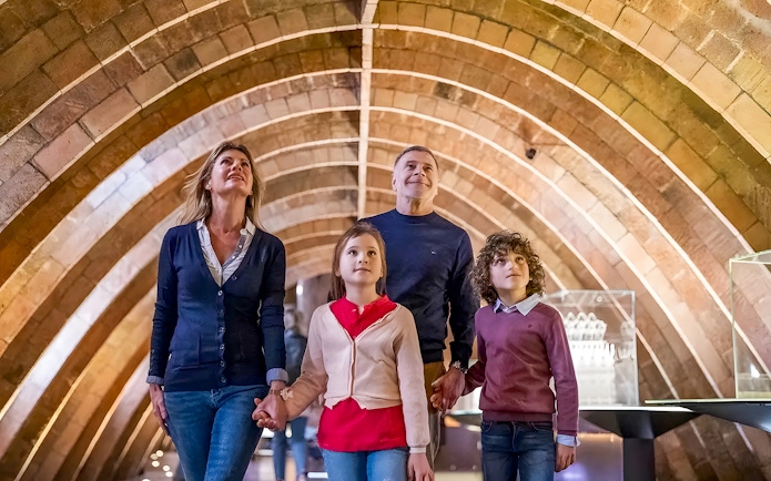 Family exploring Gaudí's La Pedrera attic arches on a guided tour in Barcelona.