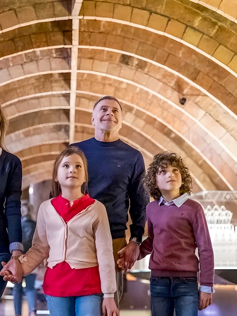 Family exploring Gaudí's La Pedrera attic arches on a guided tour in Barcelona.