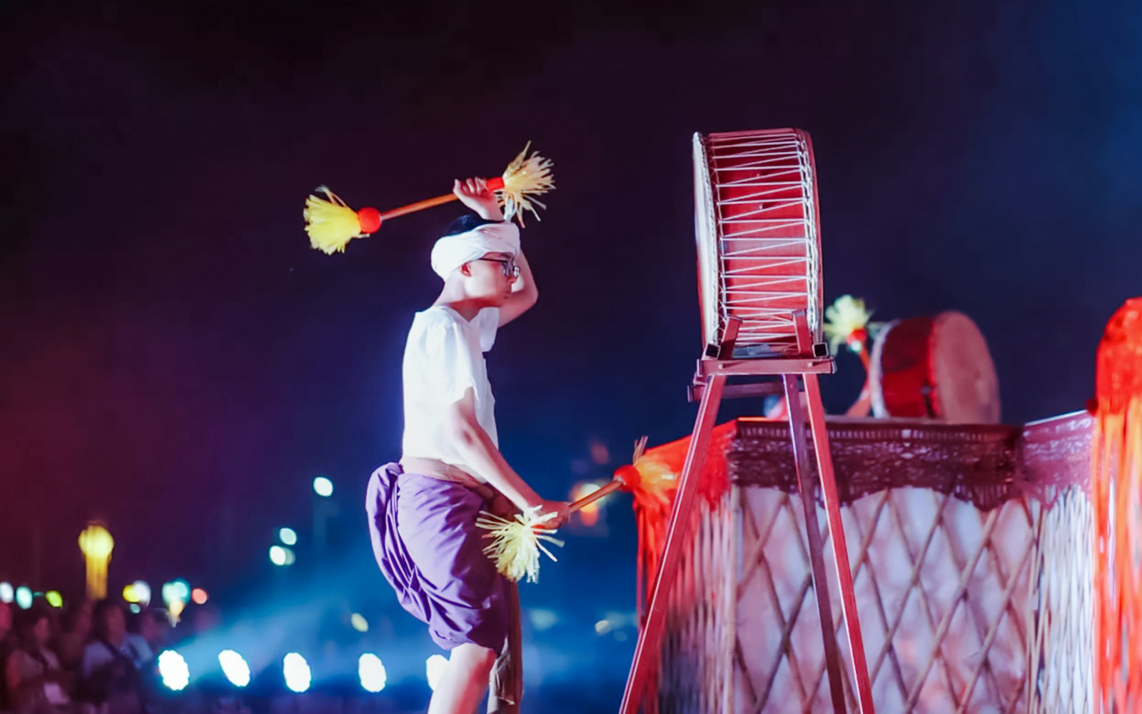 Drummer performing at Yipeng Lantern Festival, Chiang Mai, Thailand, with illuminated lanterns in the background.