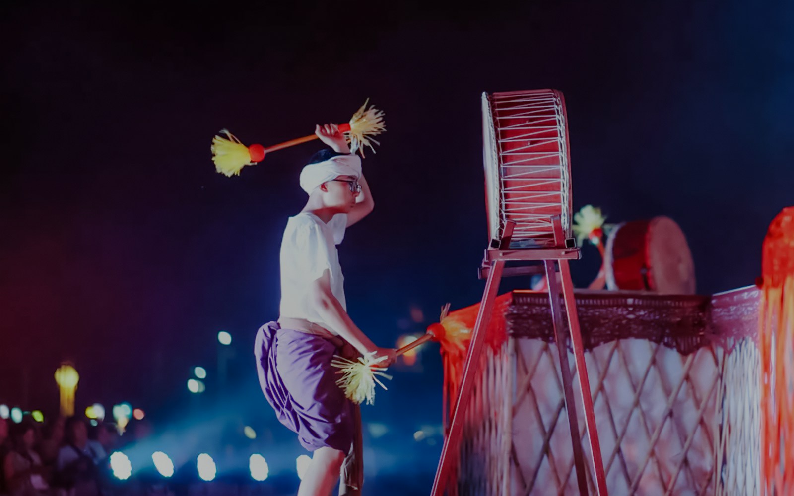 Drummer performing at Yipeng Lantern Festival, Chiang Mai, Thailand, with illuminated lanterns in the background.