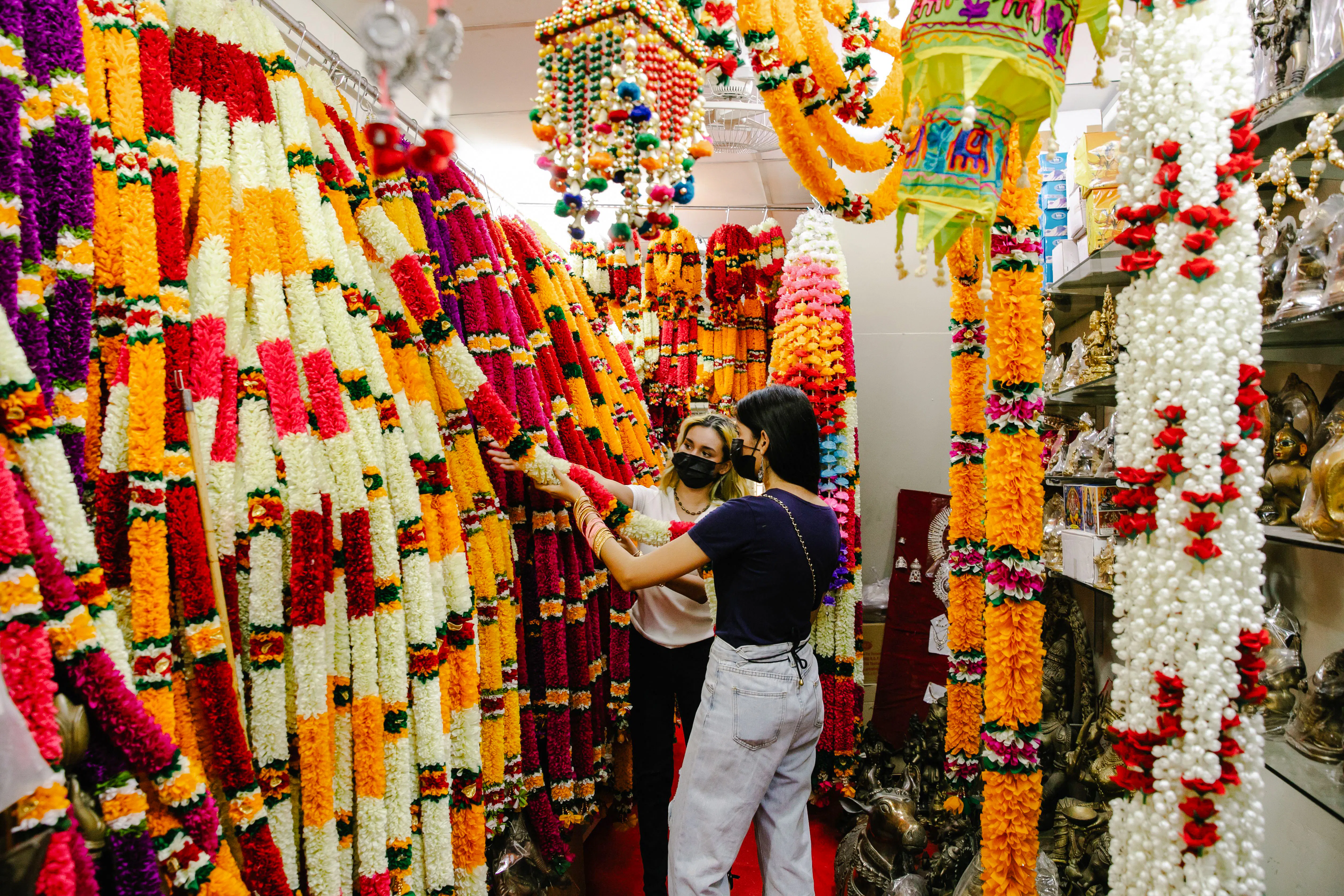 Women exploring colorful garland shop on Private Delhi Shopping Tour.