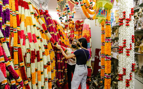 Women exploring colorful garland shop on Private Delhi Shopping Tour.