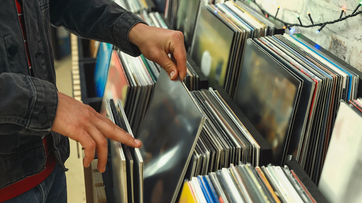 Person browsing vinyl records in a store, related to Sounds of the Universe tour.