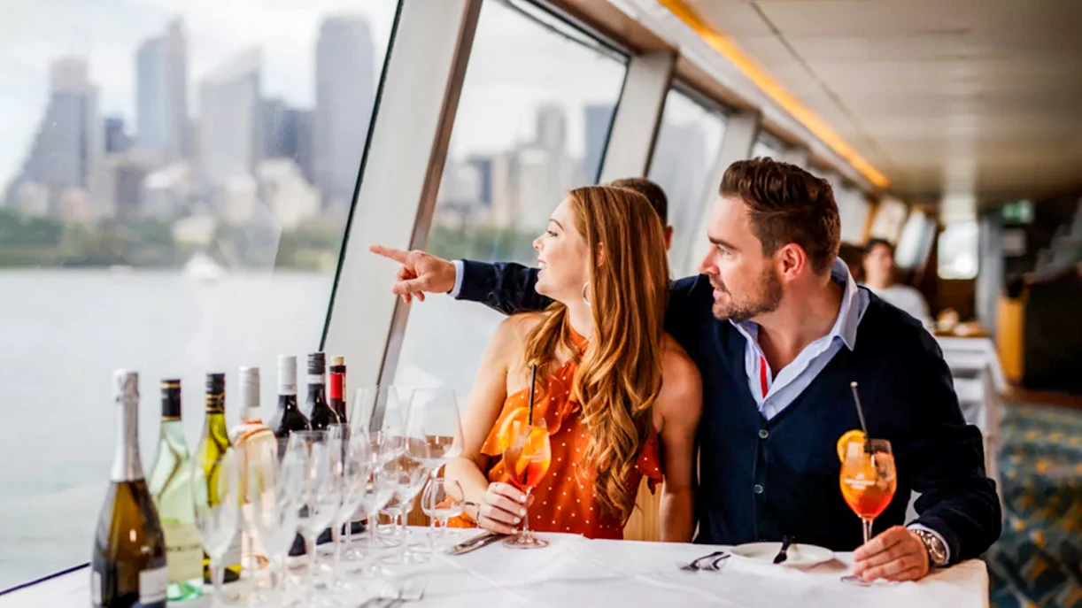Couple dining on a yacht with Sydney skyline during Sydney to Hobart Yacht Race cruise.
