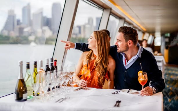 Couple dining on a yacht with Sydney skyline during Sydney to Hobart Yacht Race cruise.