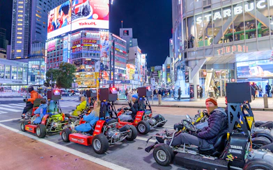 Go-karting at night in Shibuya, Tokyo, with illuminated cityscape and vibrant billboards.