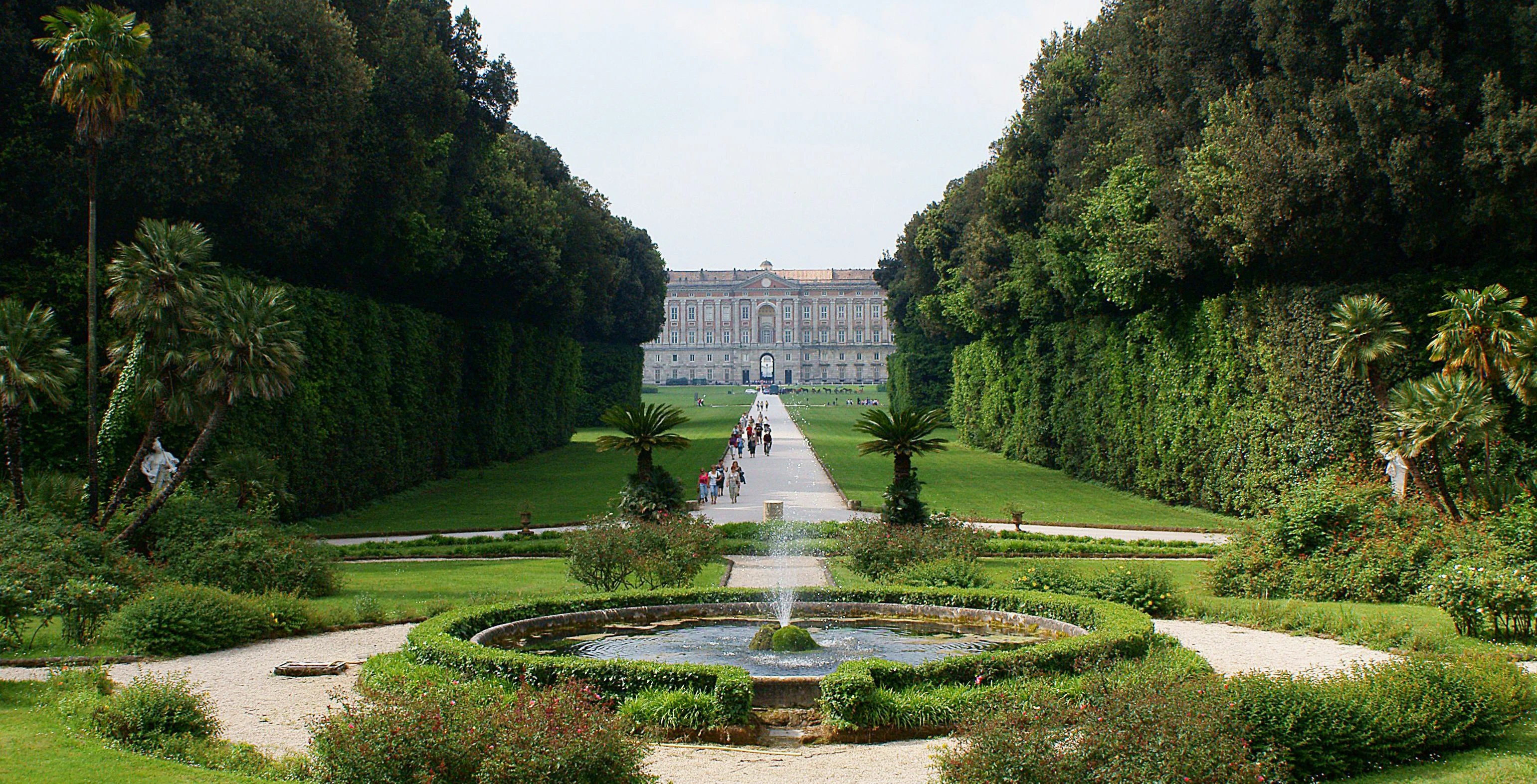 Royal Palace of Caserta garden with fountain and tree-lined path.
