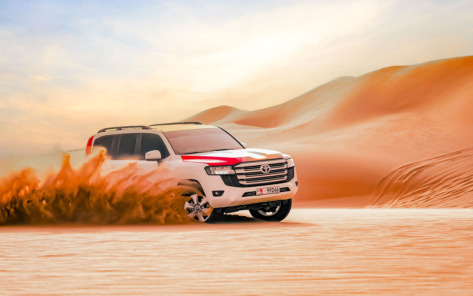 SUV driving through sand dunes in Abu Dhabi desert.
