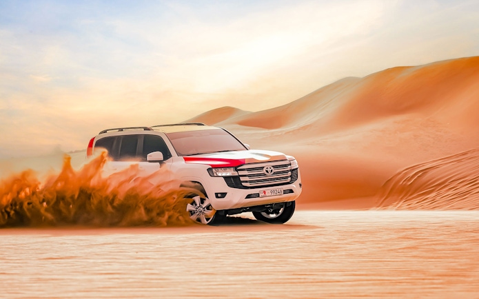 SUV driving through sand dunes in Abu Dhabi desert.