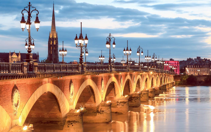 Pierre Bridge illuminated at dusk during Bateaux Bordelais dinner cruise in Bordeaux, France.