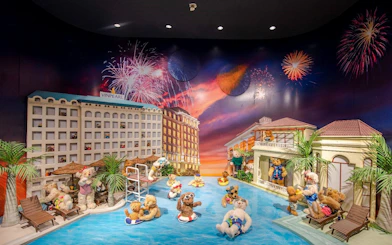 Teddy bears enjoying a pool scene with fireworks at the Teddy Bear Museum.