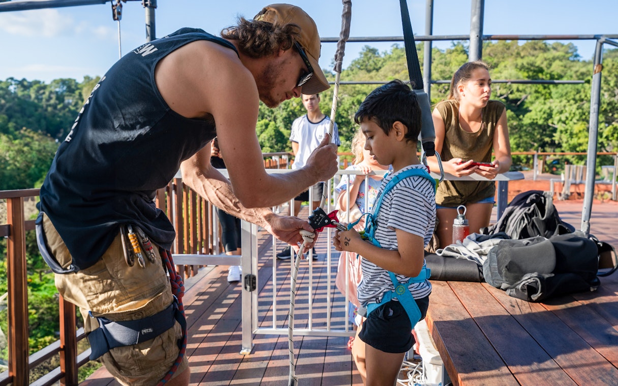 Instructor securing harness on child for Walk The Plank by AJ Hackett.
