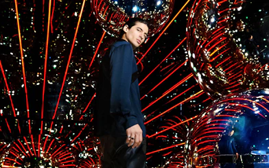 Person standing in a reflective room with red lights at AYA Universe.