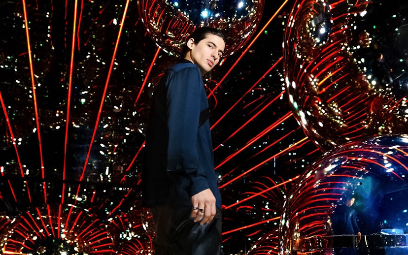 Person standing in a reflective room with red lights at AYA Universe.