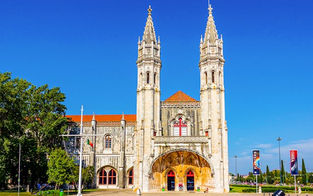Facade of the Maritime Museum in Lisbon with twin towers and red-roofed entrance.
