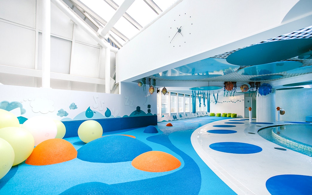 Indoor play area with colorful padded mounds and wall art at Caldea spa, Andorra.