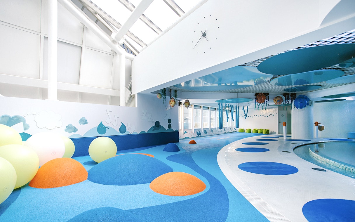 Indoor play area with colorful padded mounds and wall art at Caldea spa, Andorra.