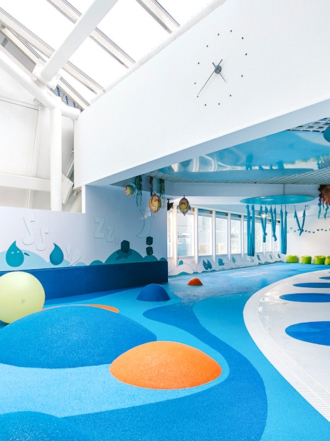 Indoor play area with colorful padded mounds and wall art at Caldea spa, Andorra.