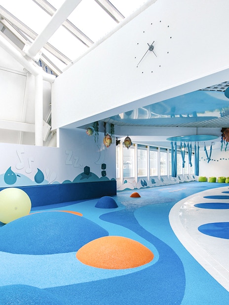 Indoor play area with colorful padded mounds and wall art at Caldea spa, Andorra.