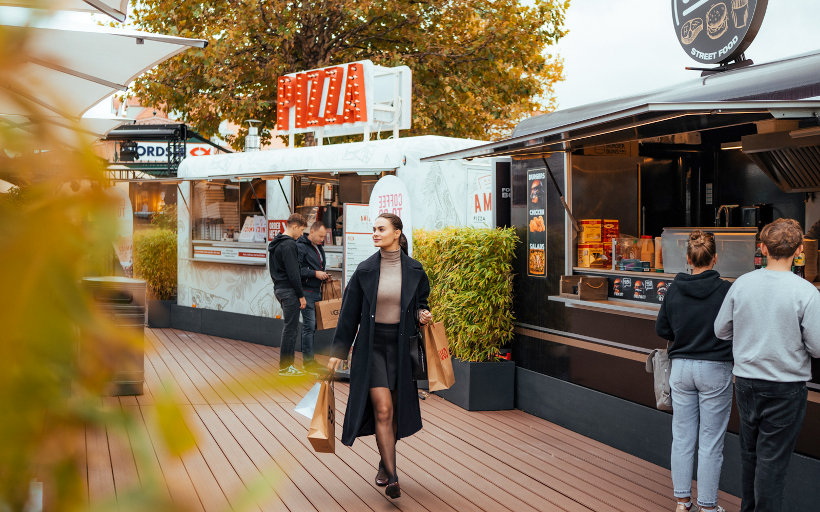Guests shopping at Parndorf Designer Outlet near Budapest with food trucks in the background.