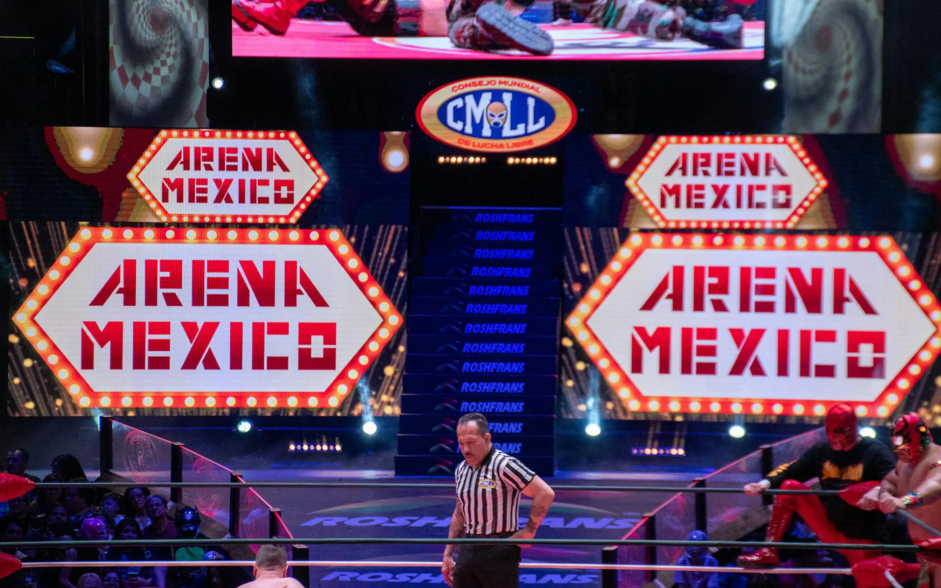 Wrestling match at Arena Mexico with luchadores and referee in the ring.