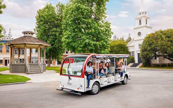 Tourists on a tram at Warner Bros. Studio, Los Angeles, with film set backdrop.