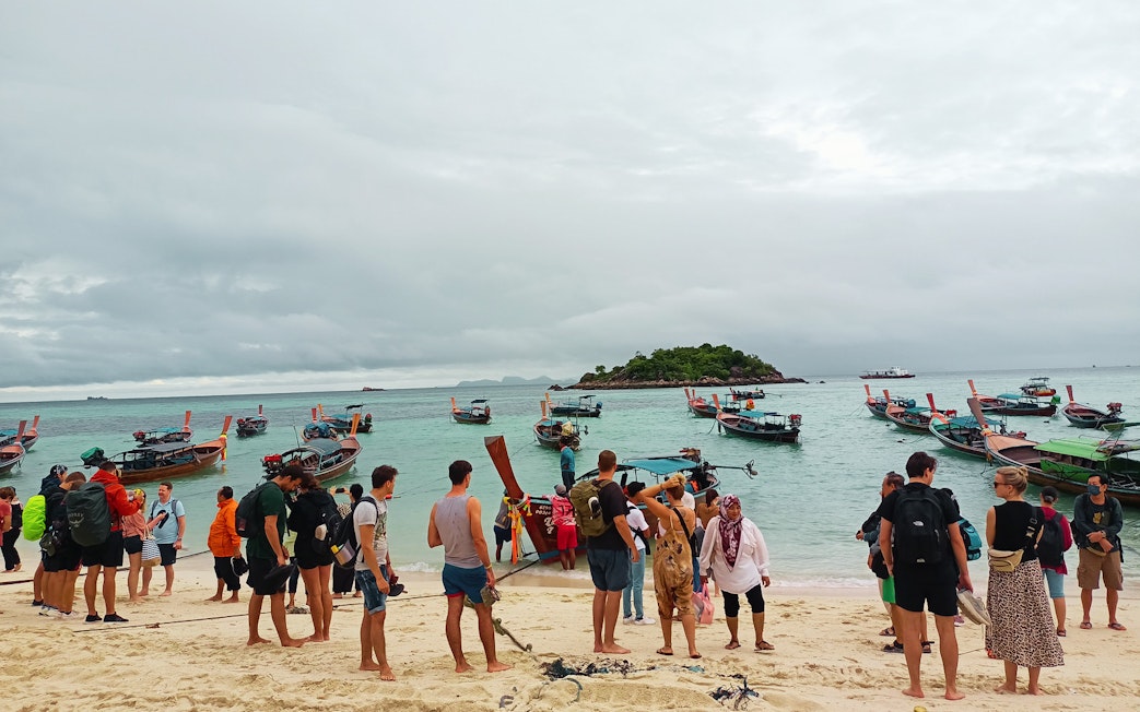 Tourists boarding long-tail boats at Koh Lipe beach for ferry to Telaga Harbour Langkawi.