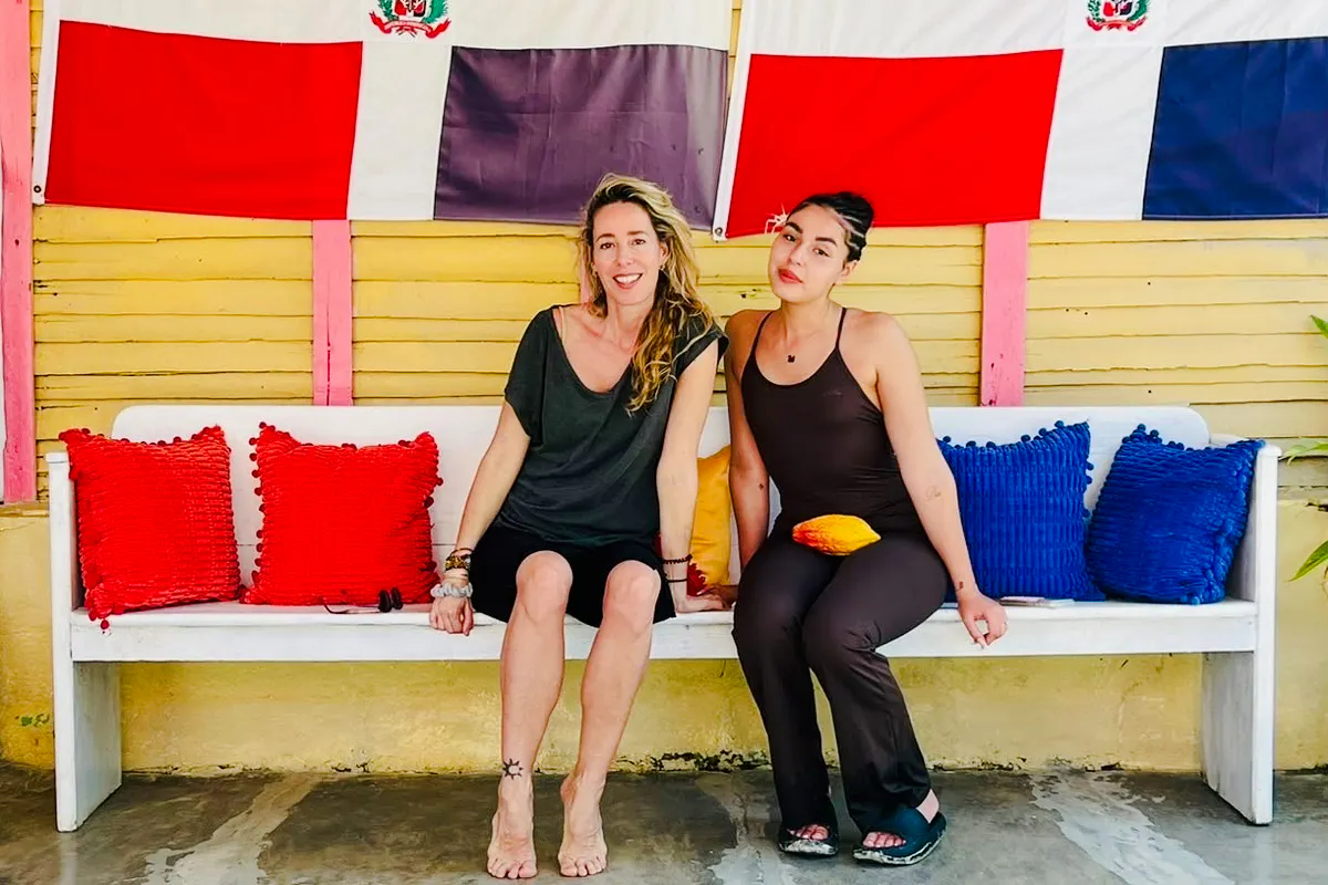 Women sitting on a bench with colorful cushions at a craft market in Punta Cana.