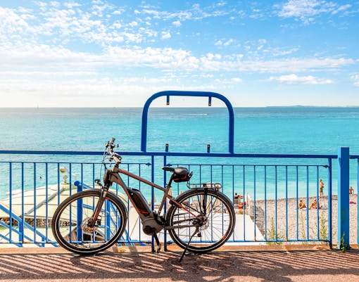 Fahrrad, geparkt entlang der Promenade des Anglais mit Blick auf das Mittelmeer in Nizza, Frankreich.