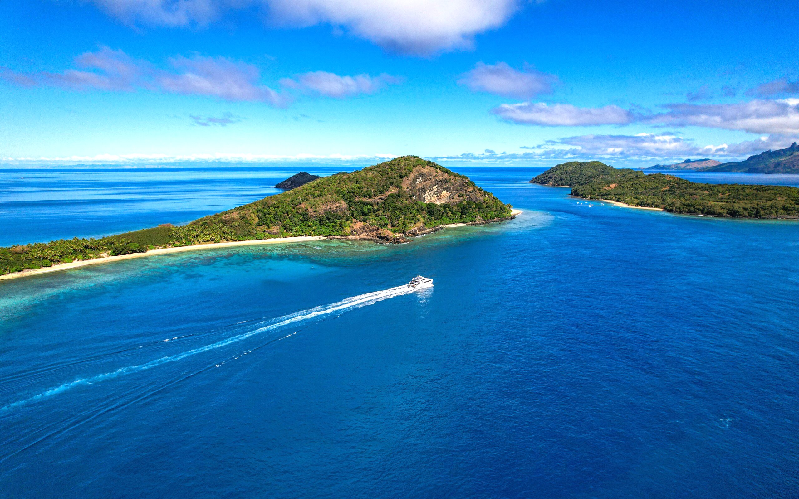 Aerial view of Manta channel near Mantaray Island Resort, Fiji, with a boat on the blue water.