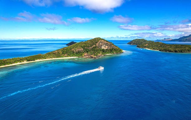 Aerial view of Manta channel near Mantaray Island Resort, Fiji, with a boat on the blue water.