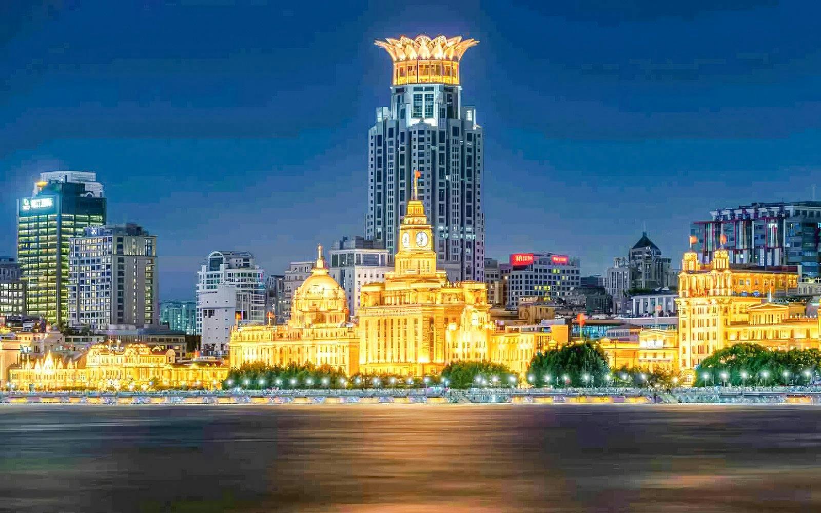Night view of the illuminated Bund skyline along the Huangpu River in Shanghai, China.
